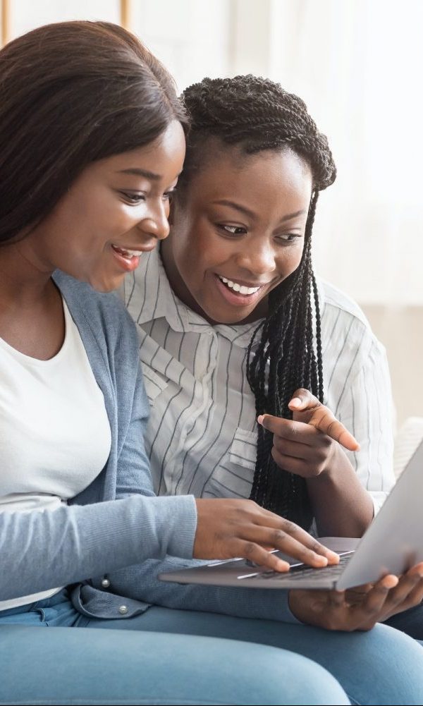 Cheerful black women browsing dating website on laptop